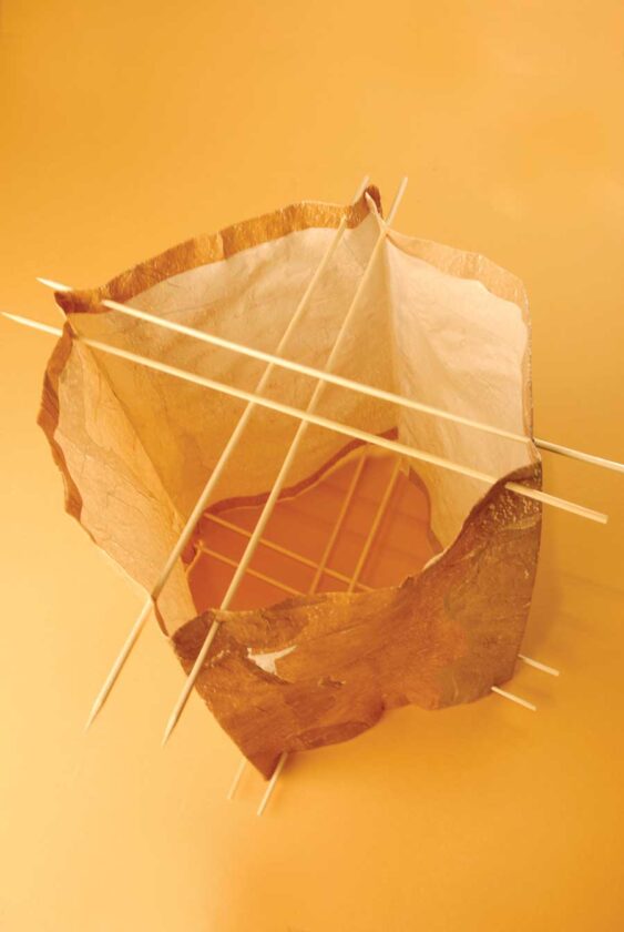 You should now have a square lampshade with two holes in each of the four corners on the top and bottom. Thread eight bamboo skewers through these corner holes on the diagonal as shown.